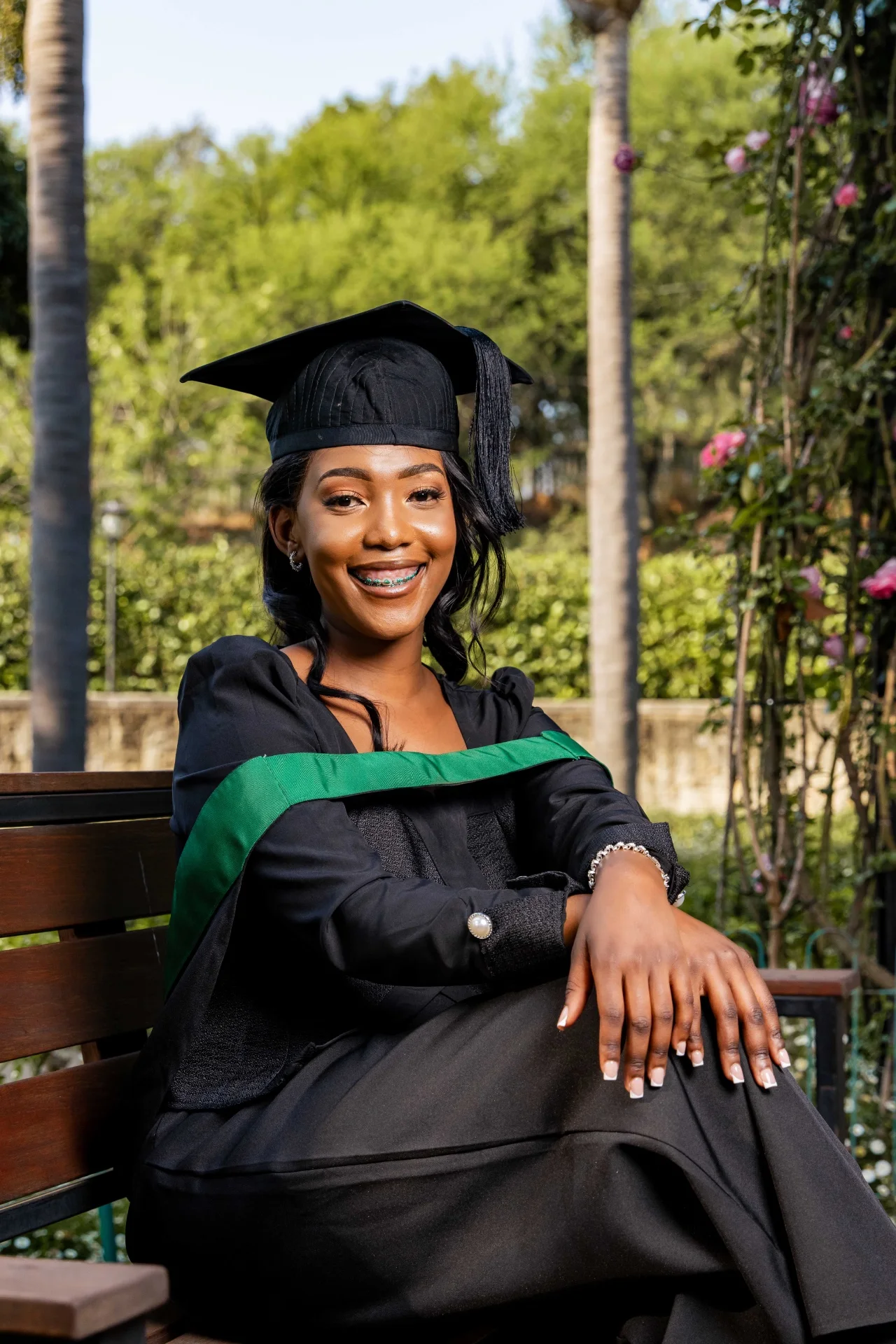 Portrait of the BeyondPink founder in her graduation gown and cap, seated on a bench in a garden.